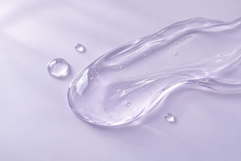 A clear serum texture on a soft lavender surface